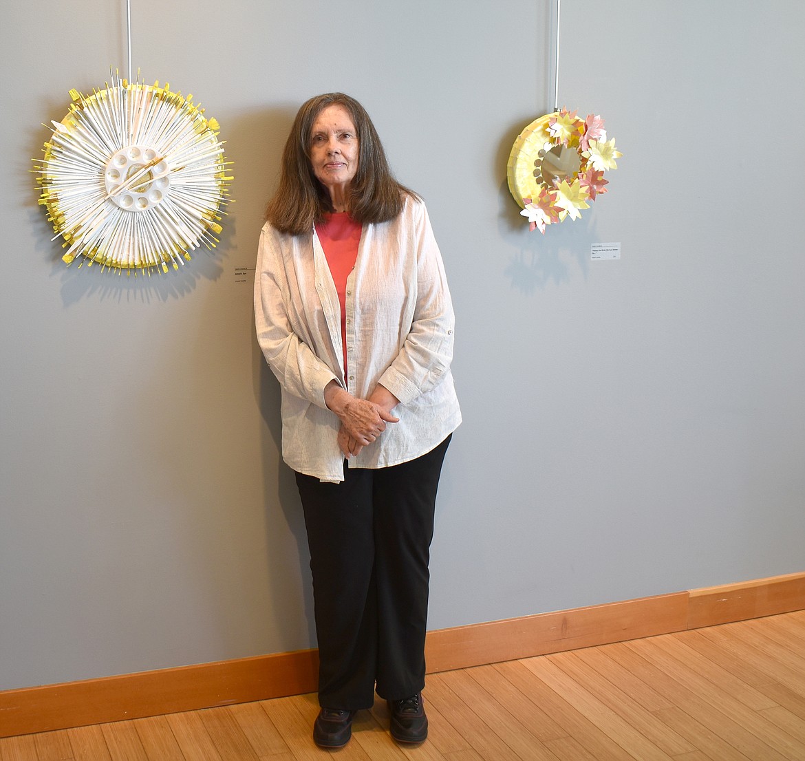 Artist Fran Church stands next to some of the pieces she has on display at the Moses Lake Museum & Art Center. The one on the left is called “Artist Sun” and is made from old paintbrushes and a painter’s palette. To the right is “Happy the Bride the Sun Shines On,” made on a tin tray with a mirror in the center.