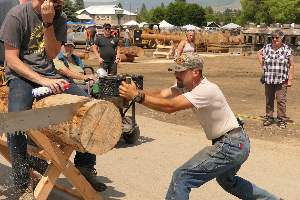 Crosscut saw event organizer Hunter Fielder gives it his all during the two-man cross-cut saw competition in the Plains VFW parking lot during Saturday's Plains Day celebration. (Chuck Bandel/VP-MI)