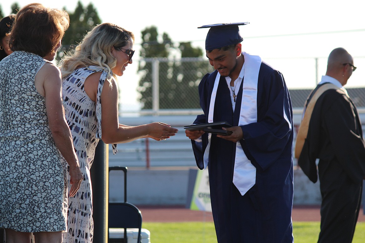 A Desert Oasis High School senior, right, smiles as he receives his diploma from Othello School Board members Thalia Lemus, center, and Sharon Schutte, left, at Monday’s graduation ceremony. The 29 students in the class of 2023 included six who earned credits as part of a SkillSource program.