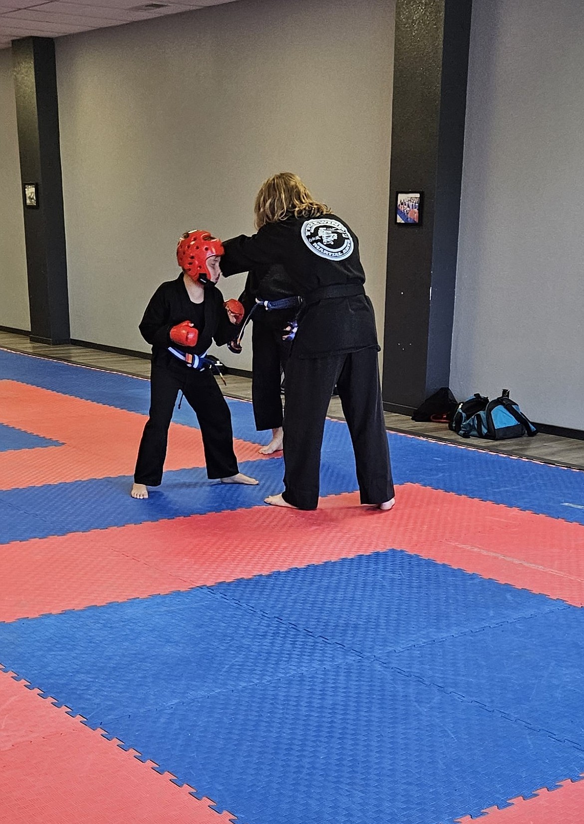 Max House, with the blue and white belt, works with a trainer during Taekwondo class.