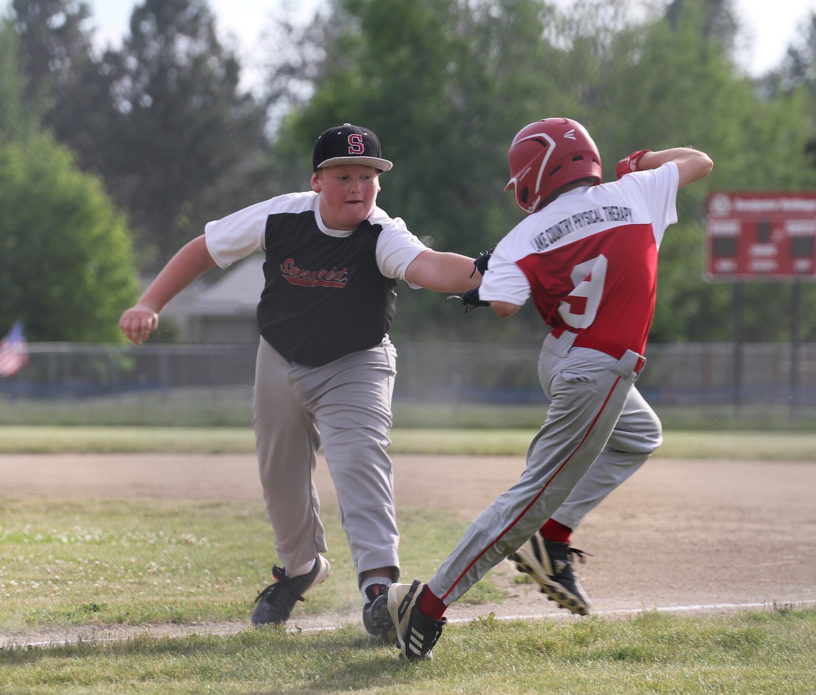 Curtis Sommerfield of the Juniors Black tags out Wyatt Buday at first base.