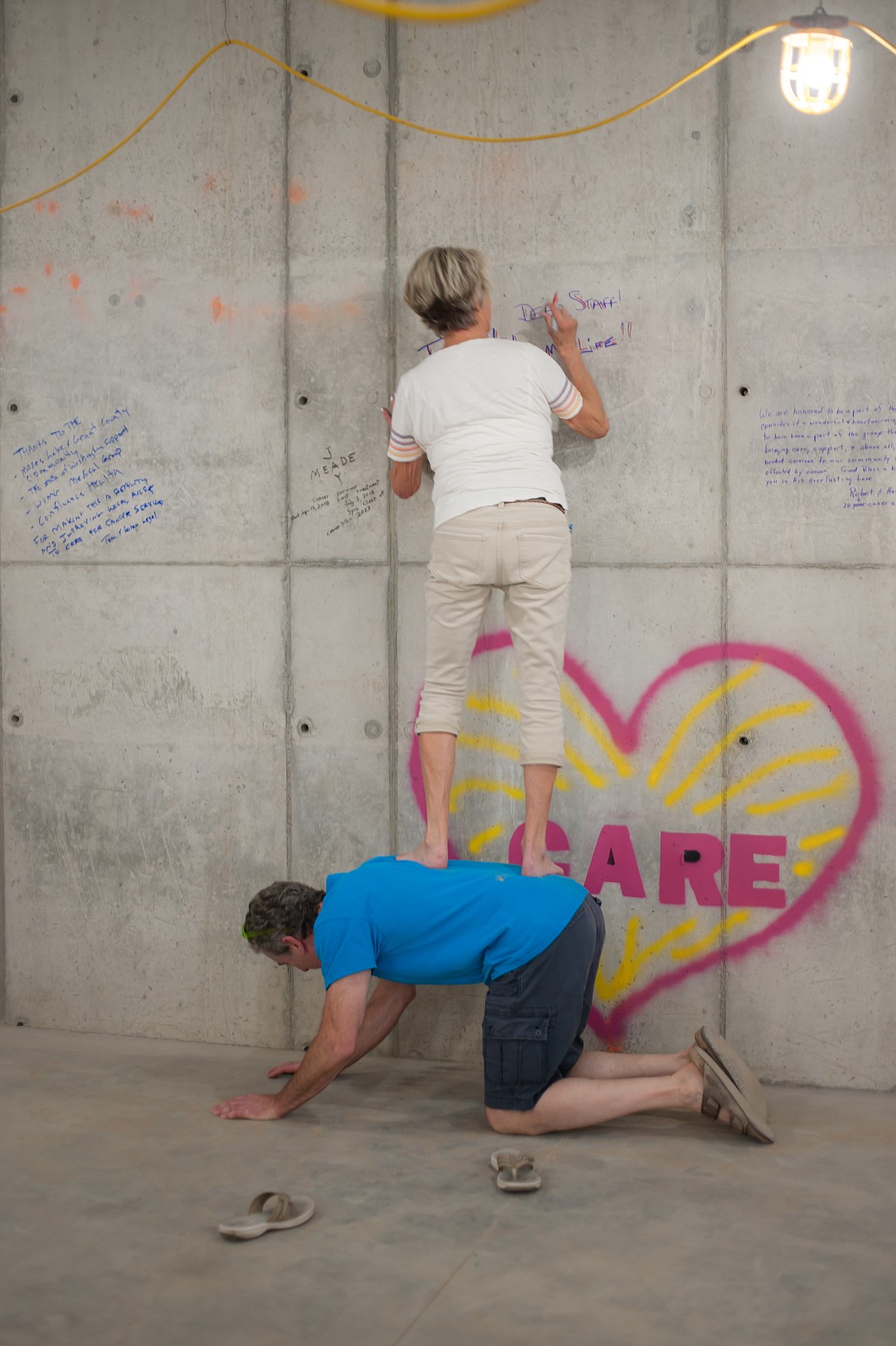 A cancer survivor gets some help to write words of gratitude and support during the Written in Stone event.