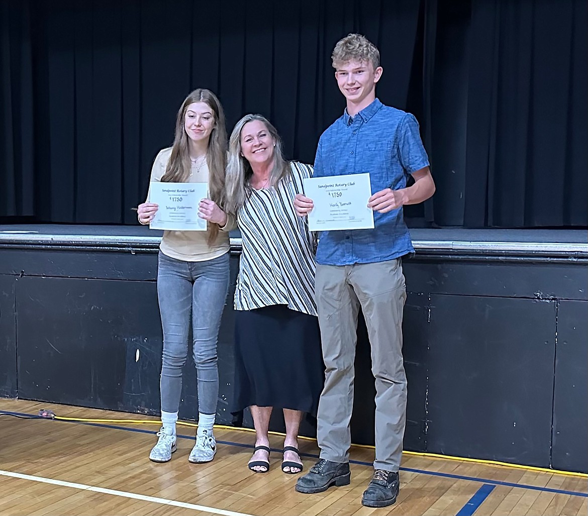 Clark Fork High School seniors Hank Barnett and Bethany Holderman receive their scholarship awards from Rotarian Dyno Wahl.
