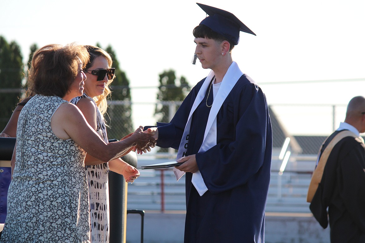 A Desert Oasis High School graduate accepts his diploma from Othello School Board member Sharon Schutte.