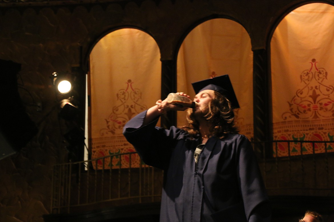 Forrest Bird Charter School graduate Daniel Landry chugs a bottle of coffee that he won in a bet with government teacher Mark Webber after receiving his diploma.