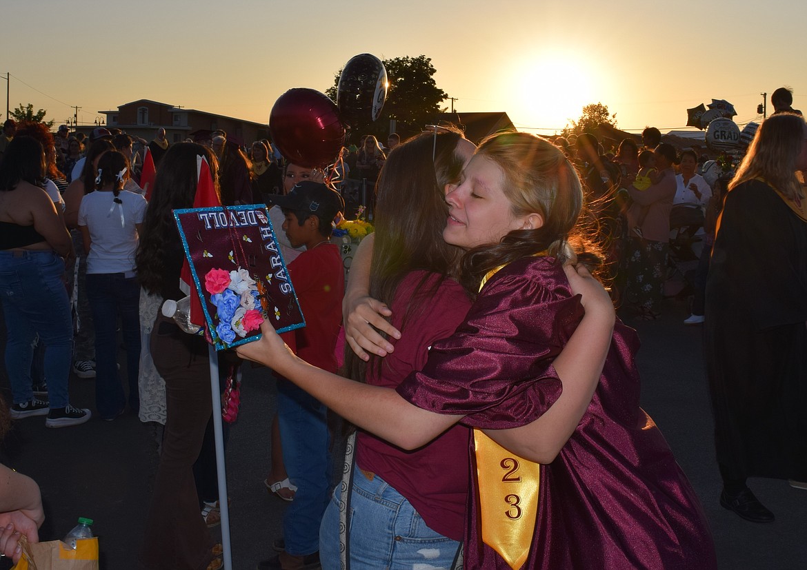 A 2023 graduate of Moses Lake High School grabs a hug from someone special with the sun setting in the background and her cap – also known as a mortarboard – decked out for graduation.