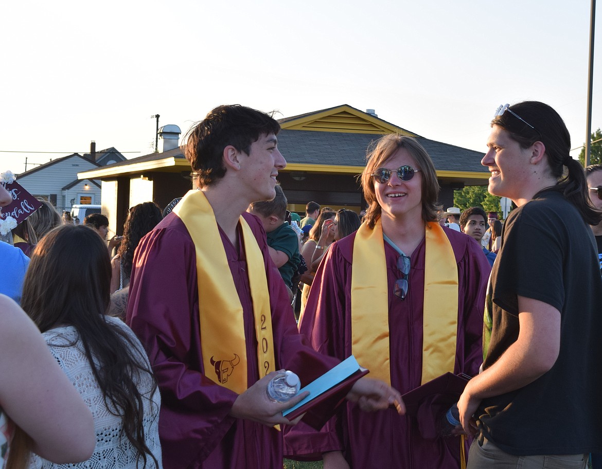 Two 2023 Mavericks grads visit with a friend after the Moses Lake High School graduation at Lions Field.