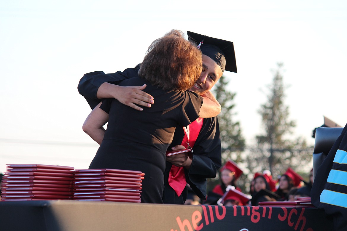 An Othello senior gets his diploma, and a hug, from Othello School Board member Sharon Schutte