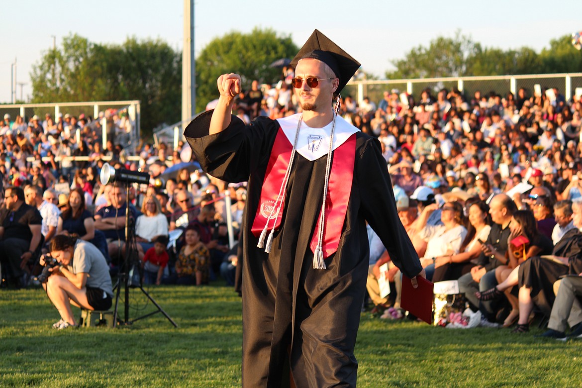 On the way back to his seat a brand-new Othello graduate points to a classmate in a congratulatory gesture.