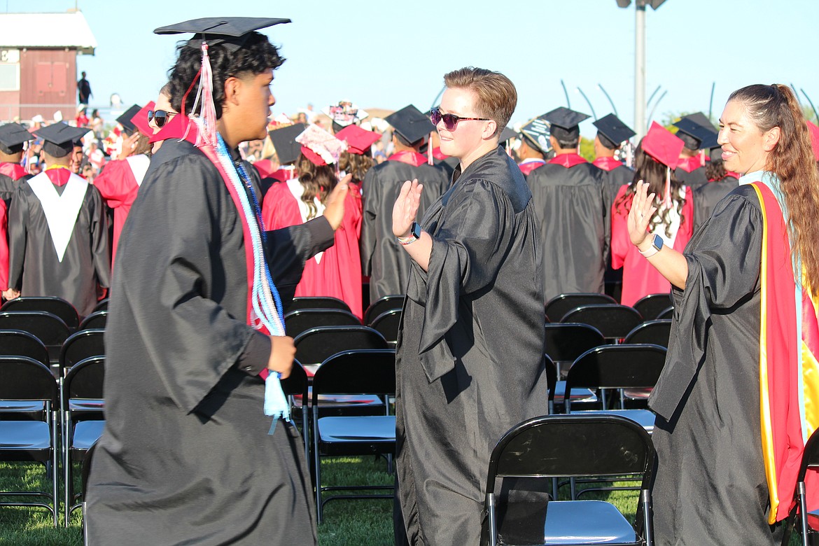 An Othello High School teacher exchanges a high-five with a senior during graduation ceremonies on June 2.