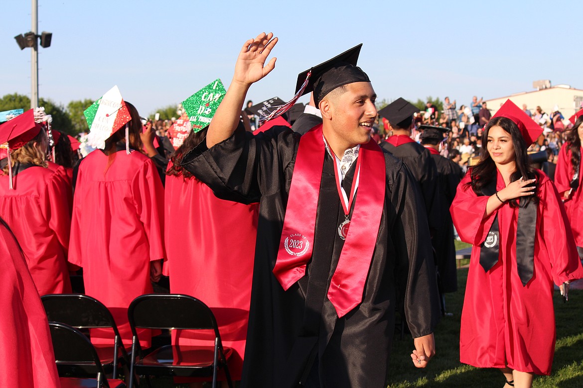 An Othello senior waves to the crowd while entering Huskie Stadium during graduation ceremonies.