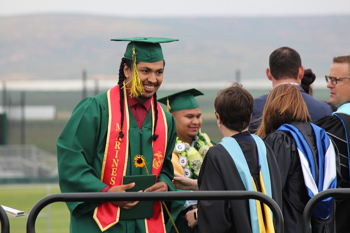 A brand-new Quincy graduate is congratulated by administrators.