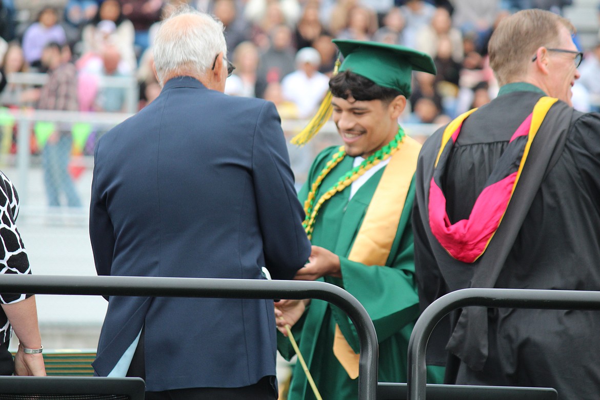 A Quincy graduate receives his diploma from Quincy School Board member Chris Baumgartner, left.