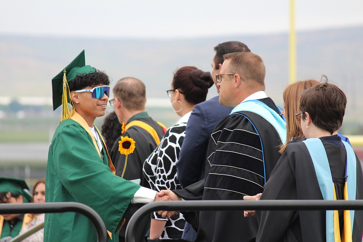 A graduating Quincy High School senior gets a handshake from Quincy Superintendent Nik Bergman, right.