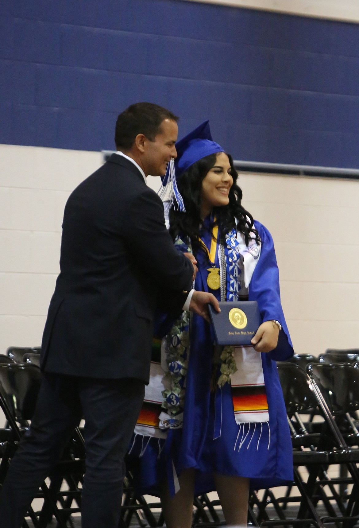 A Soap Lake graduate receives her diploma during the school’s graduation ceremony on Saturday, smiling to the crowd for a photo.