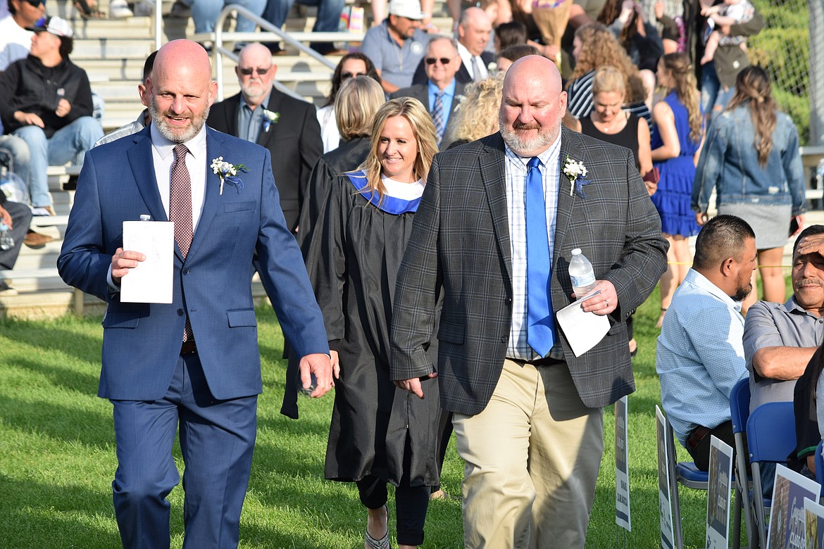 Warden School District Superintendent Scott West, left front, and School Board Chair Bryce Box, right front, are followed by Warden High School Principal Katie Phipps as they walk onto the field prior to the start of Warden’s 2023 graduation ceremony June 9.