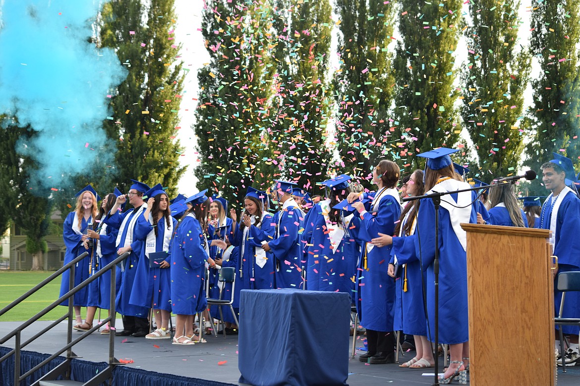 Members of the class of 2023 celebrate with confetti poppers and smoke canisters at the end of Warden High School’s graduation ceremony.