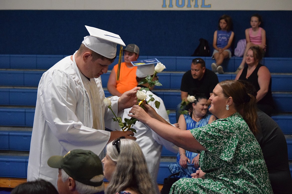 Wilson Creek High School graduate Dominic Armstrong presents a white rose to a family member during the school’s 2023 graduation ceremony. A regular part of the school’s ceremony, students present the roses to family members and friends as a way of showing their appreciation.