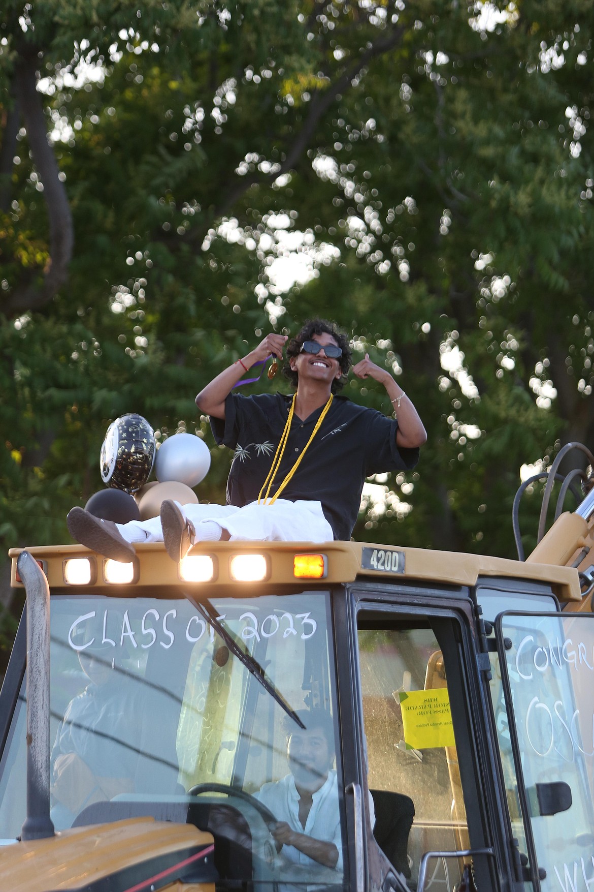 A Wahluke High School graduate sits atop a backhoe during the graduation parade.