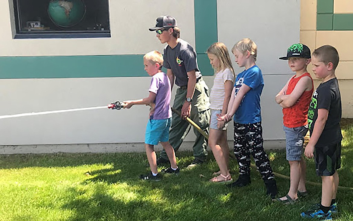 A firefighter helps students at Idaho Hill Elementary try out a firehouse during a recent visit to the school.