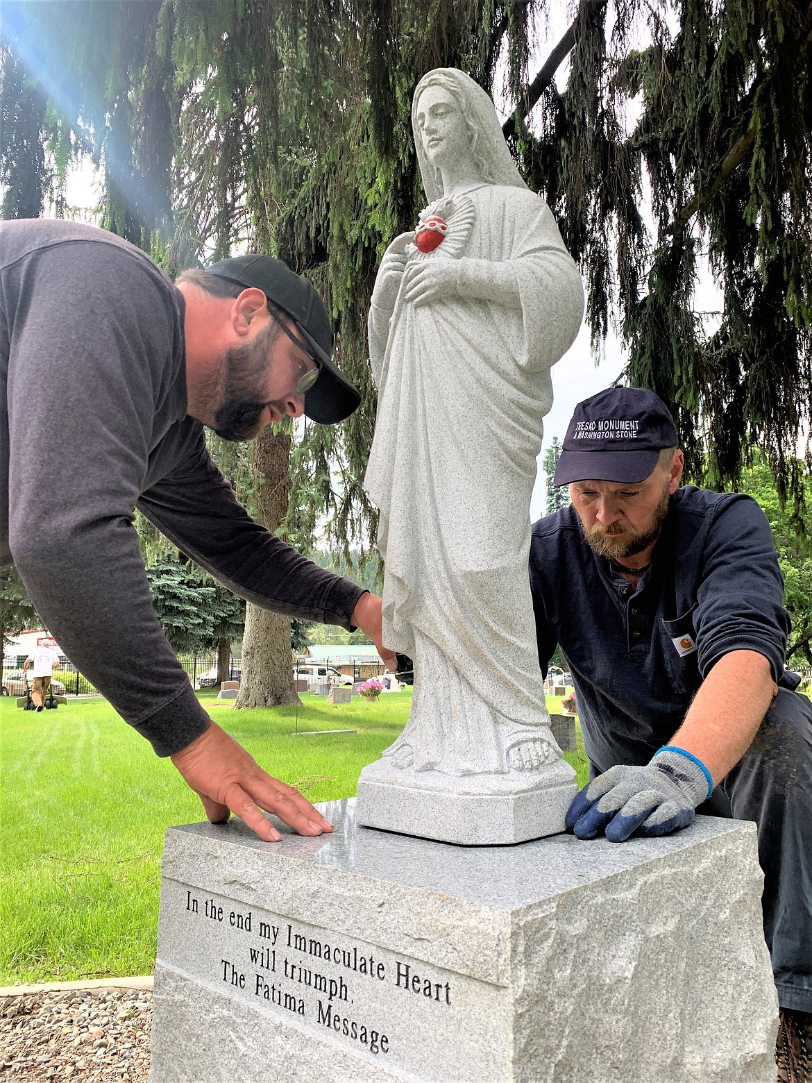 Chris Lane, left, and Randy Brown with Tresko Monument Inc. install an Immaculate Heart of Mary statue at St. Thomas Catholic Cemetery on Wednesday.