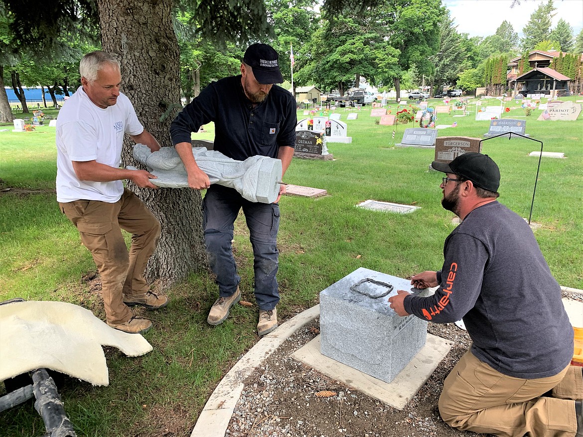Alex Razimkov and Randy Brown carry a statue of Michael the Archangel while Chris Lane waits to put it in place at St. Thomas Catholic Cemetery on Wednesday.