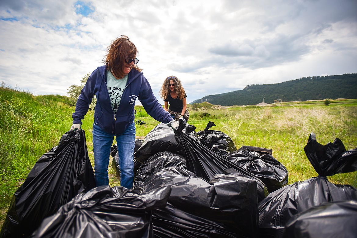 Lisa Simmer, front, and Dawn Tacke haul bags of garbage to a truck during a Clean Up Community Day organized by the Homeless Outreach team of Collaborative Housing Solutions of Northwest Montana in Kalispell on Thursday, June 15. (Casey Kreider/Daily Inter Lake)