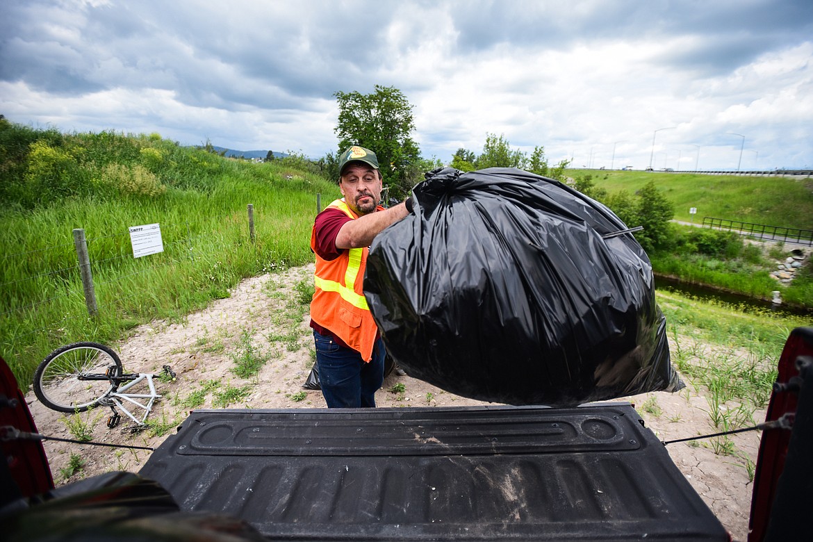 Travis White, an employee at the Flathead Warming Center, loads bags of garbage into the back of a truck during a Clean Up Community Day organized by the Homeless Outreach team of Collaborative Housing Solutions of Northwest Montana in Kalispell on Thursday, June 15. (Casey Kreider/Daily Inter Lake)