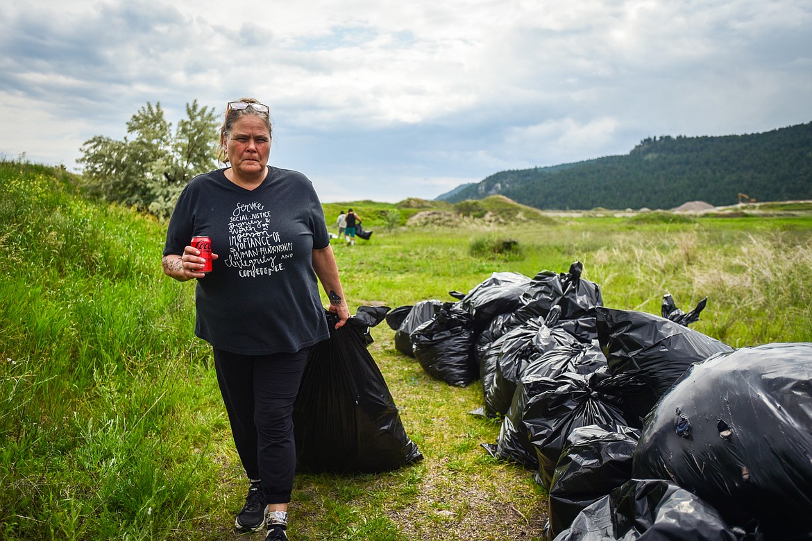 Audrey Tri, operations director at the Flathead Warming Center, hauls a bag of garbage to a truck during a Clean Up Community Day organized by the Homeless Outreach team of Collaborative Housing Solutions of Northwest Montana in Kalispell on Thursday, June 15. (Casey Kreider/Daily Inter Lake)
