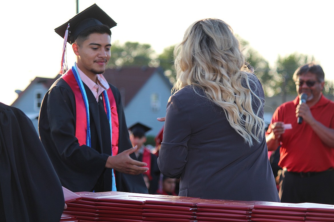 An Othello High School senior receives his diploma with a solemn smile.