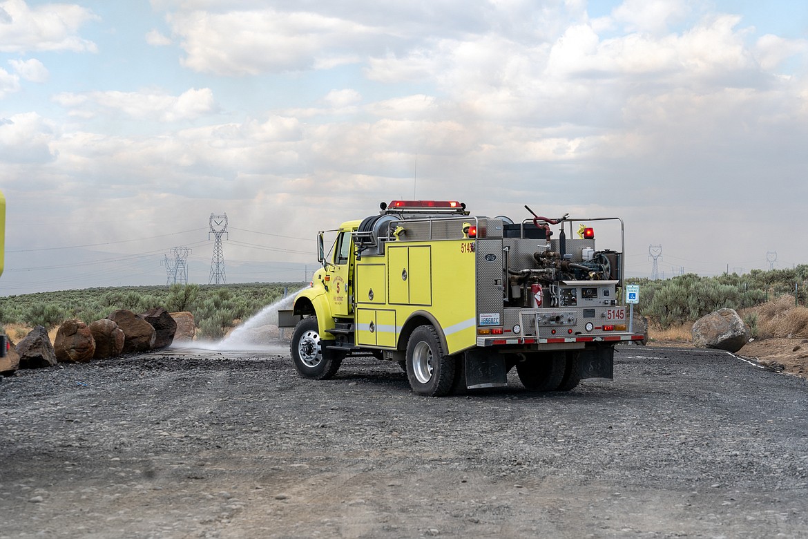 A fire truck douses flames with water near Rocky Ford Creek between Ephrata and Moses Lake on Wednesday.