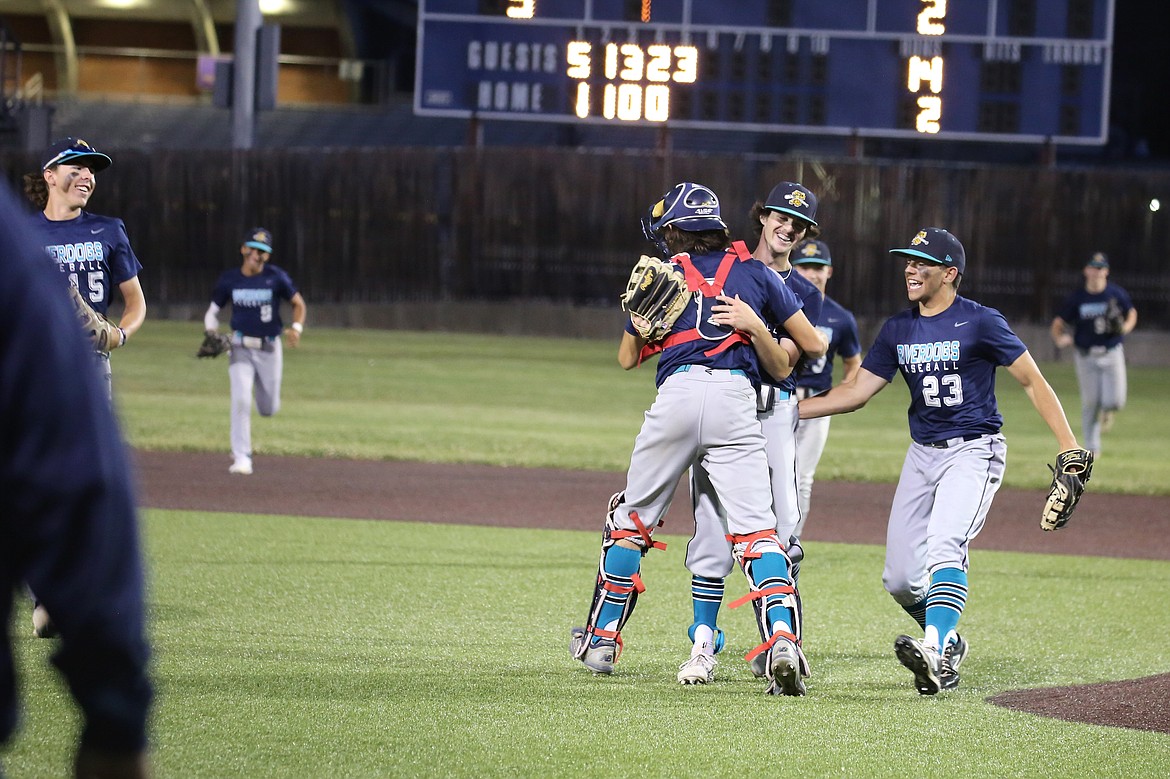 River Dog catcher Holden Koziol, center left, hugs pitcher Alex Roker, center right, while first baseman Cooper Hancock (23) joins to celebrate during a game against Columbia River on Wednesday.