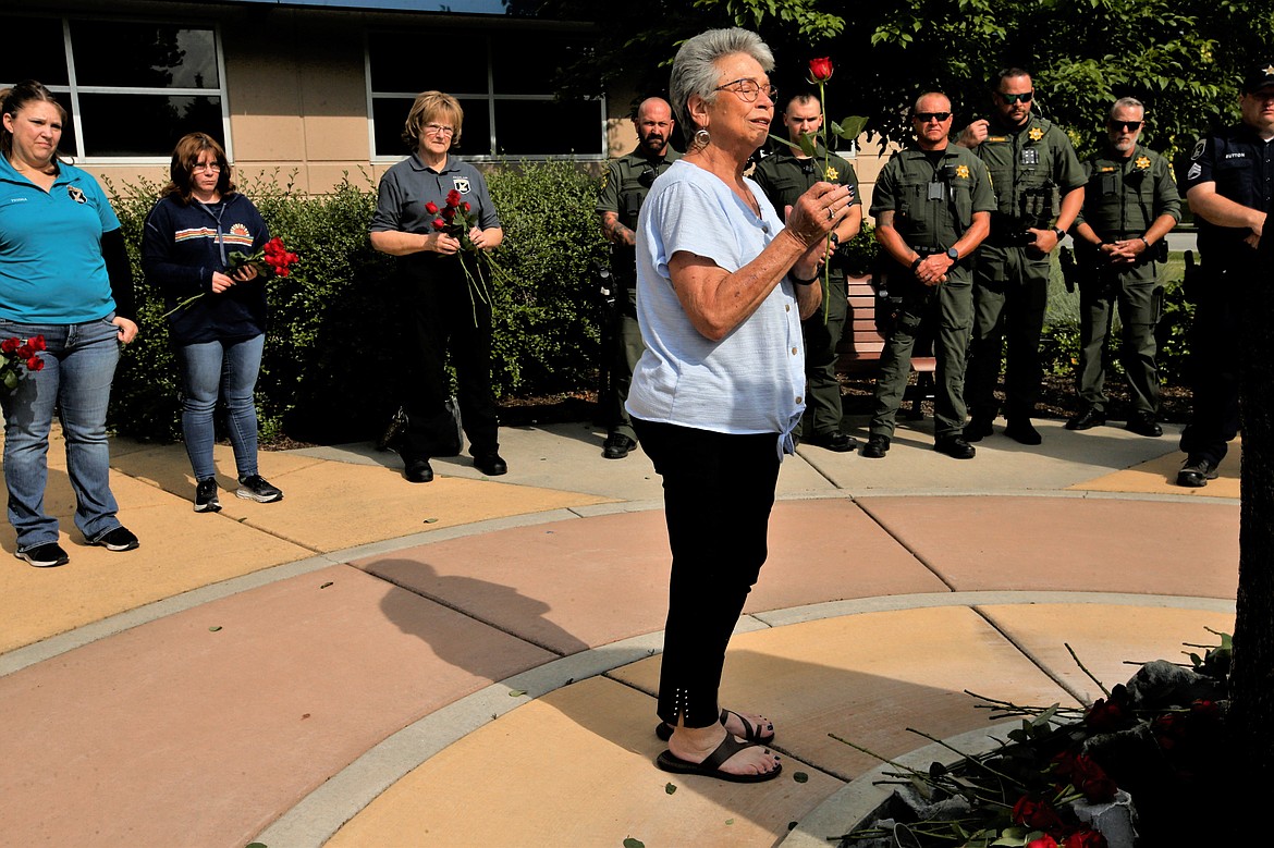 Glenna McGill pauses before placing a rose at the base of the fountain during a rose-laying ceremony in the Linda Huff Memorial Plaza outside the ISP Region 1 headquarters on Friday.