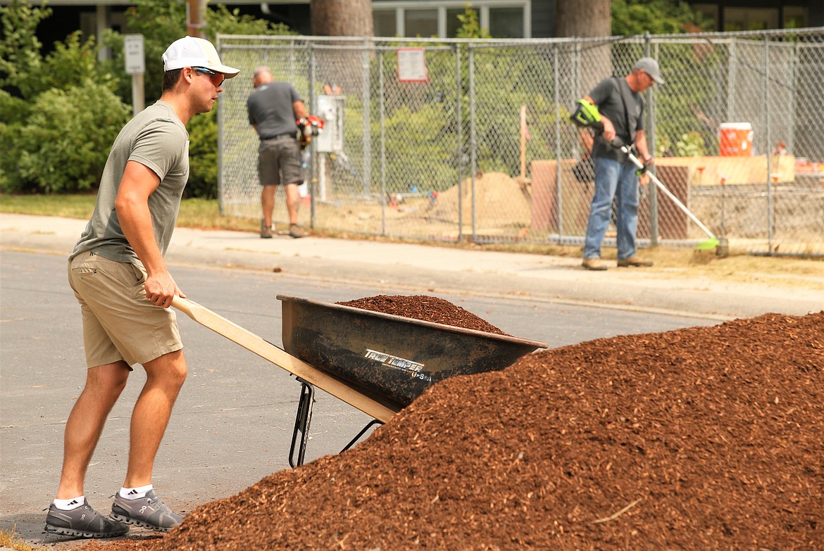 Mike Hamilton pushes a wheelbarrow of bark during Windermere Realty Coeur d'Alene's Community Service Day at Children's Village on Friday.