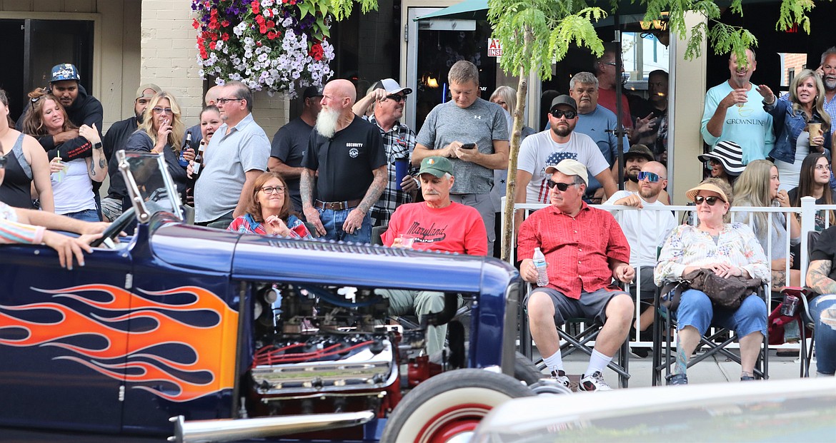 A crowd watches a vintage vehicle with flames flow past in the cruise Friday.