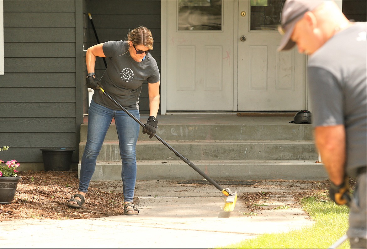 Heidi Miller sweeps during Windermere Realty Coeur d'Alene's Community Service Day at Children's Village on Friday.