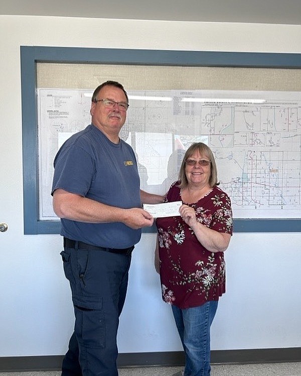 Caring Neighbors Board member Kristy Rattray presents Adams County Fire District 5 Chief Gary Lebacken with a $2,375 donation Thursday.