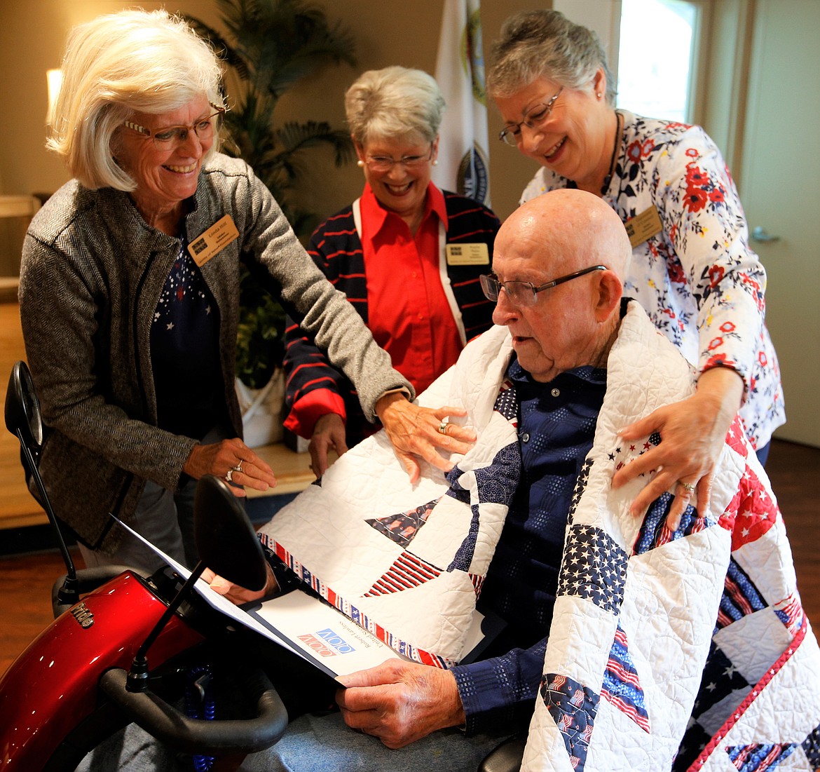 Robert Lawless receives a Quilt of Valor from Linda Hill, Kayla Main and Giannine O'Connor on Sunday.