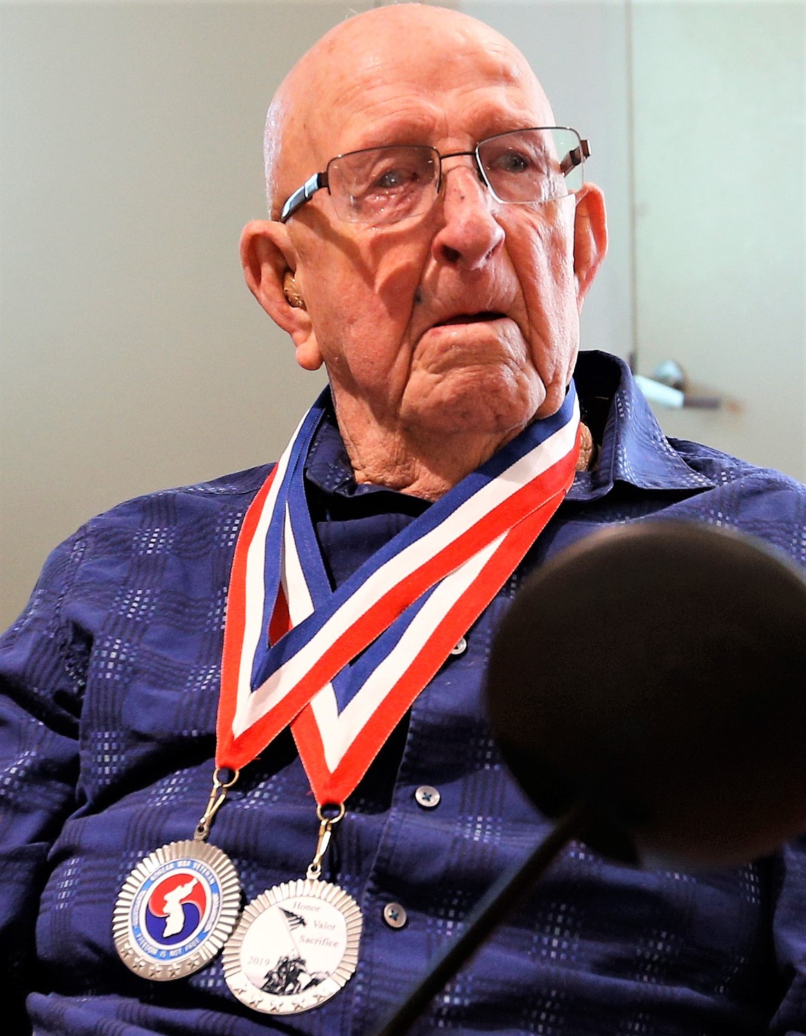 Robert Lawless looks up with two medallions around his neck he received Sunday for his service as a medic with the Army.