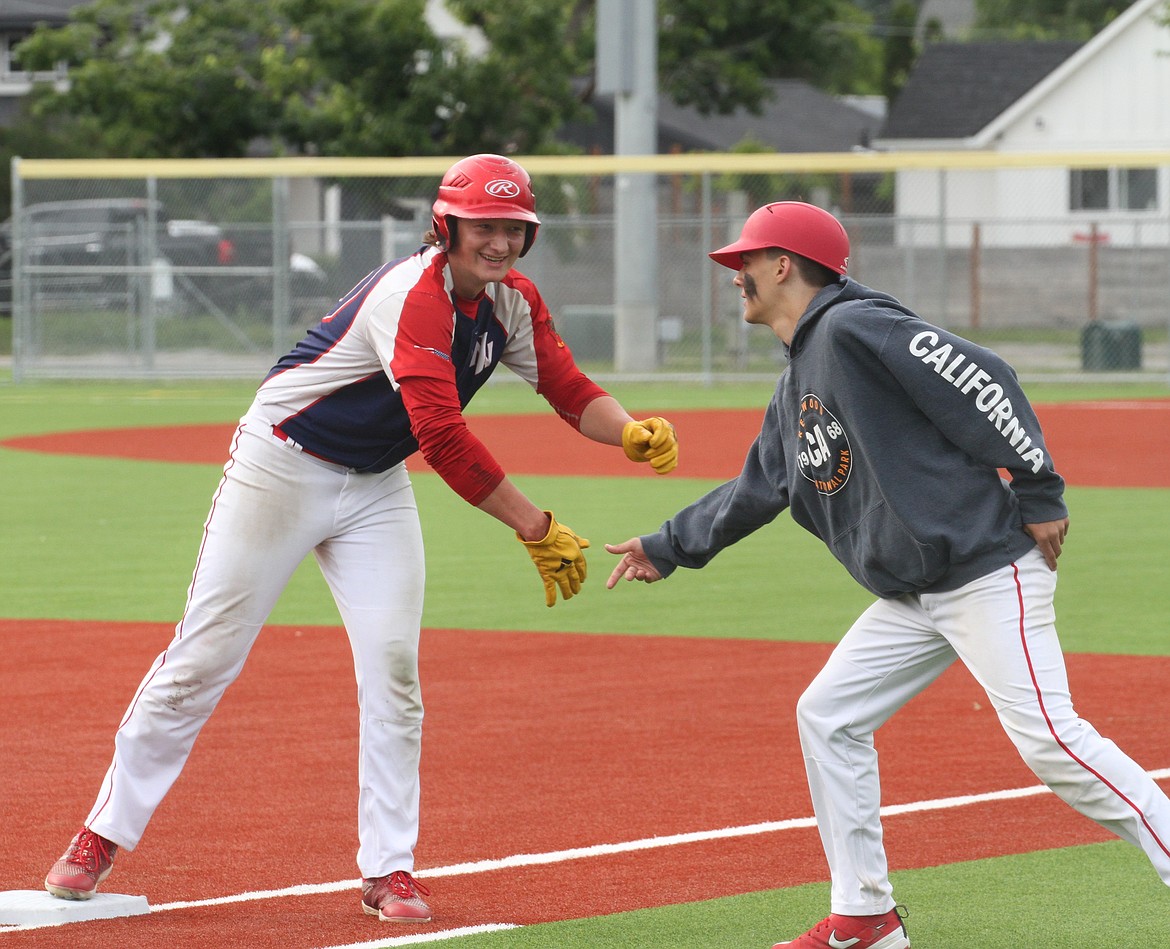 Zeke Roop high-fives a teammate at first base after a single in the bottom of the third inning.