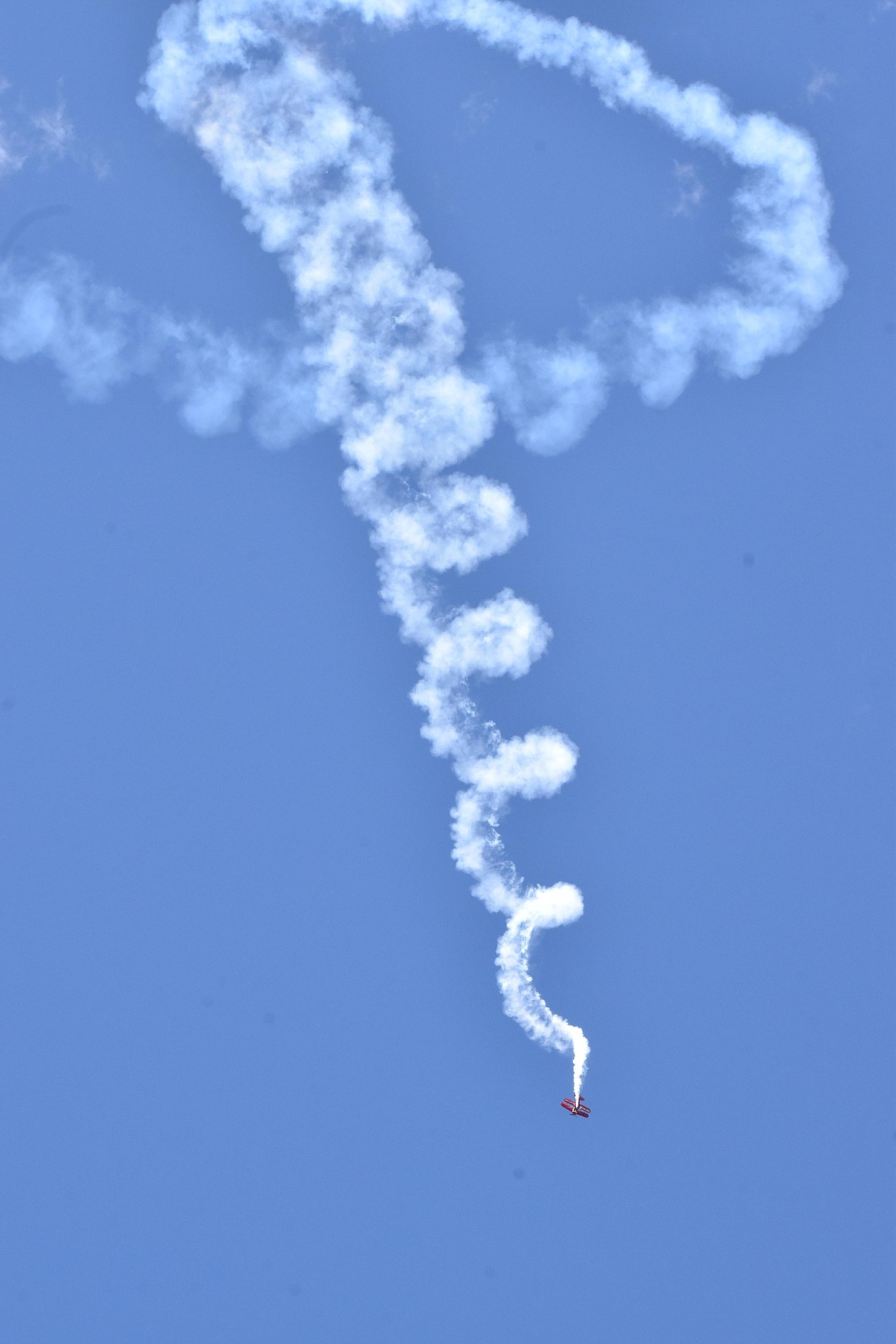 A biplane trailing smoke – don’t worry, it was intentional – makes a spiral pattern during an acrobatics exercise designed to delight spectators at the Moses Lake Airshow.
