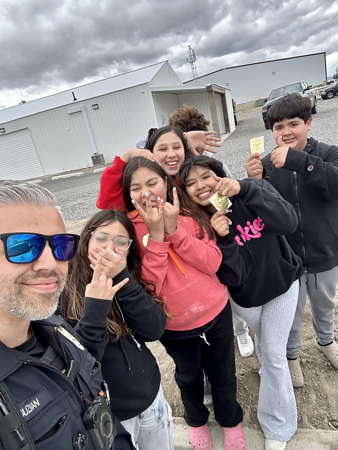 Abraham Guzman, Quincy PD school resource officer, left, snaps a picture with some Quincy students just before 2023 spring vacation.