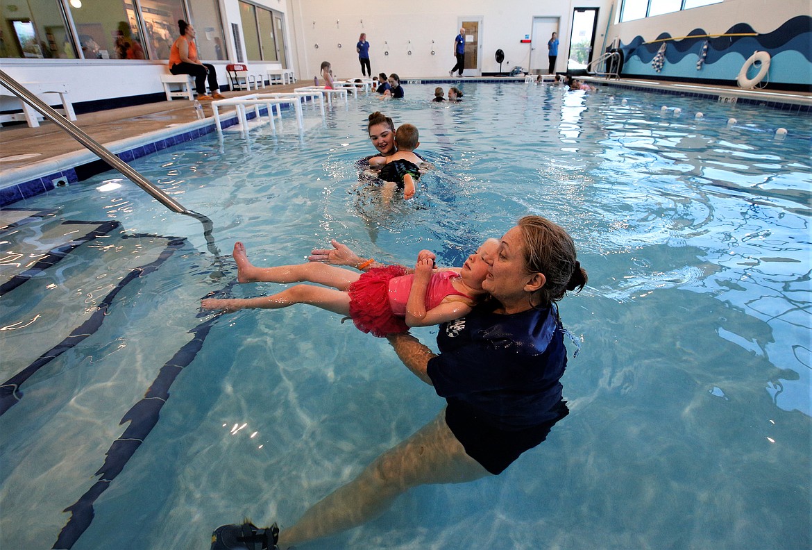 Gina Larson helps a child in the Safe Splash Swim School pool on Thursday.