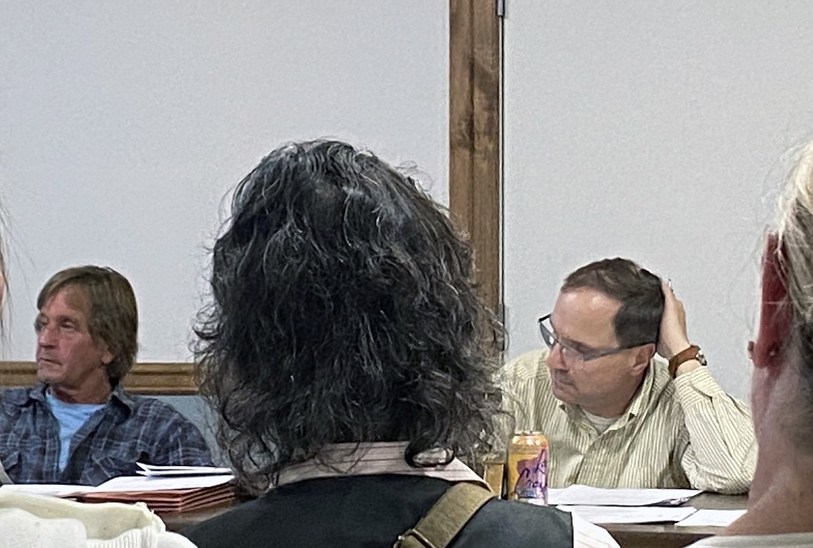 West Bonner County School District board trustees Troy Reinbold, left, and Keith Rutledge, right, listen as parents express their frustration over the presence of possibly armed volunteer guards at Wednesday's board meeting.