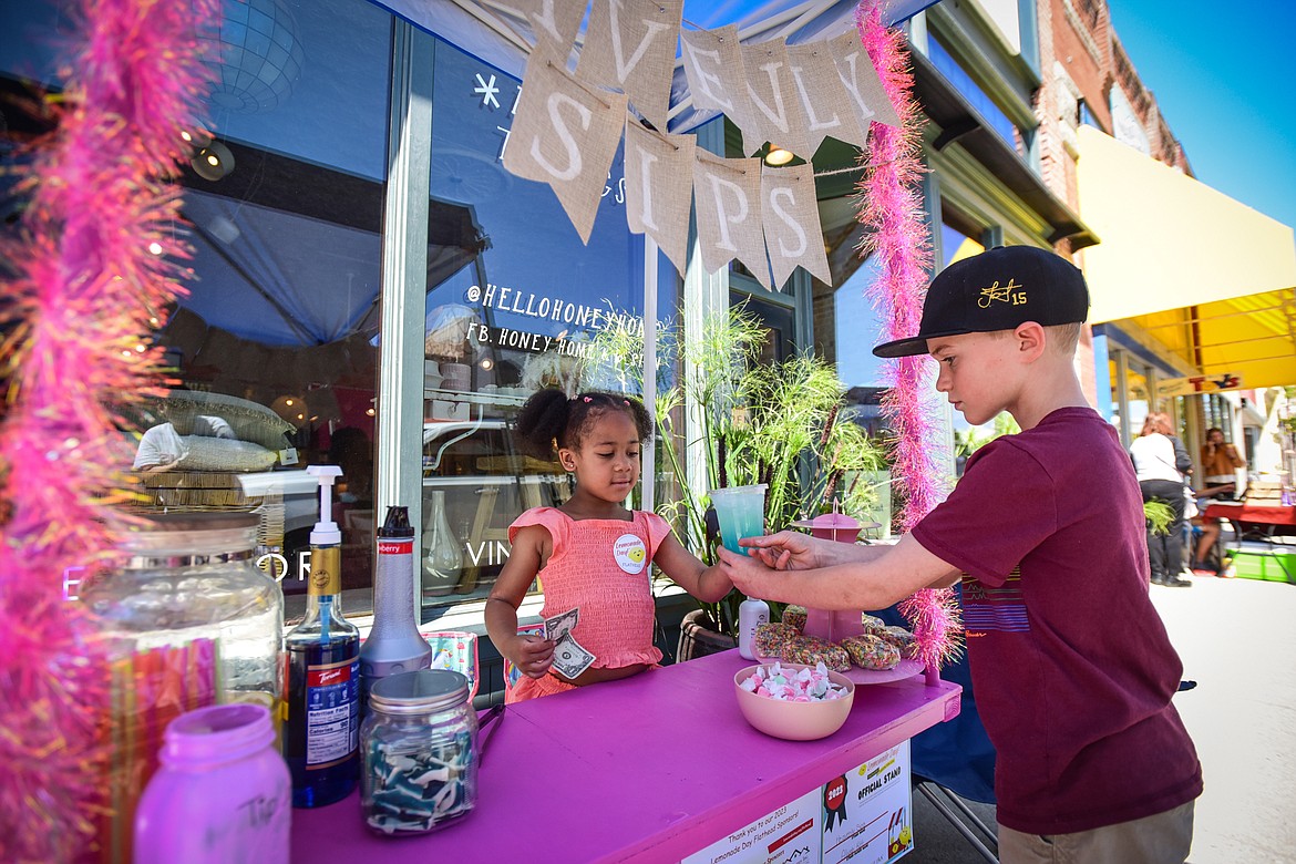 Joel Williams, right, buys a cup of Shark Attack from Aliyah Kitt at her Heavenly Sips stand serving Classic Lemonade, Barbie Lemonade, Shark Attack, Caramel Brownies and Fruity Pebbles as part of the Lemonade Day program on Saturday, June 24. (Casey Kreider/Daily Inter Lake)