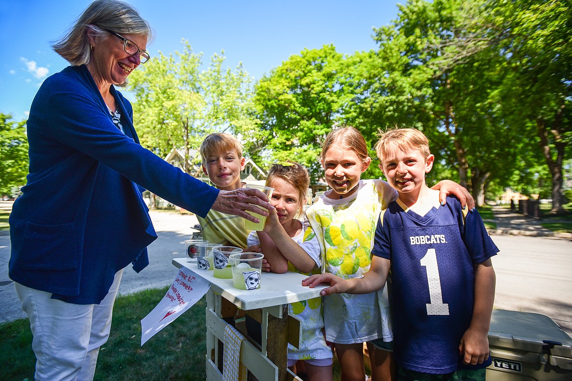 Joan Clark, left, purchases a cup of lemonade from Reid, Lucy, Parker and Regan Waldenberg and their stand named The Lemons, serving lemonade, lime lemonade, pineapple lemonade and brownies as part of the Lemonade Day program on Saturday, June 24. (Casey Kreider/Daily Inter Lake)