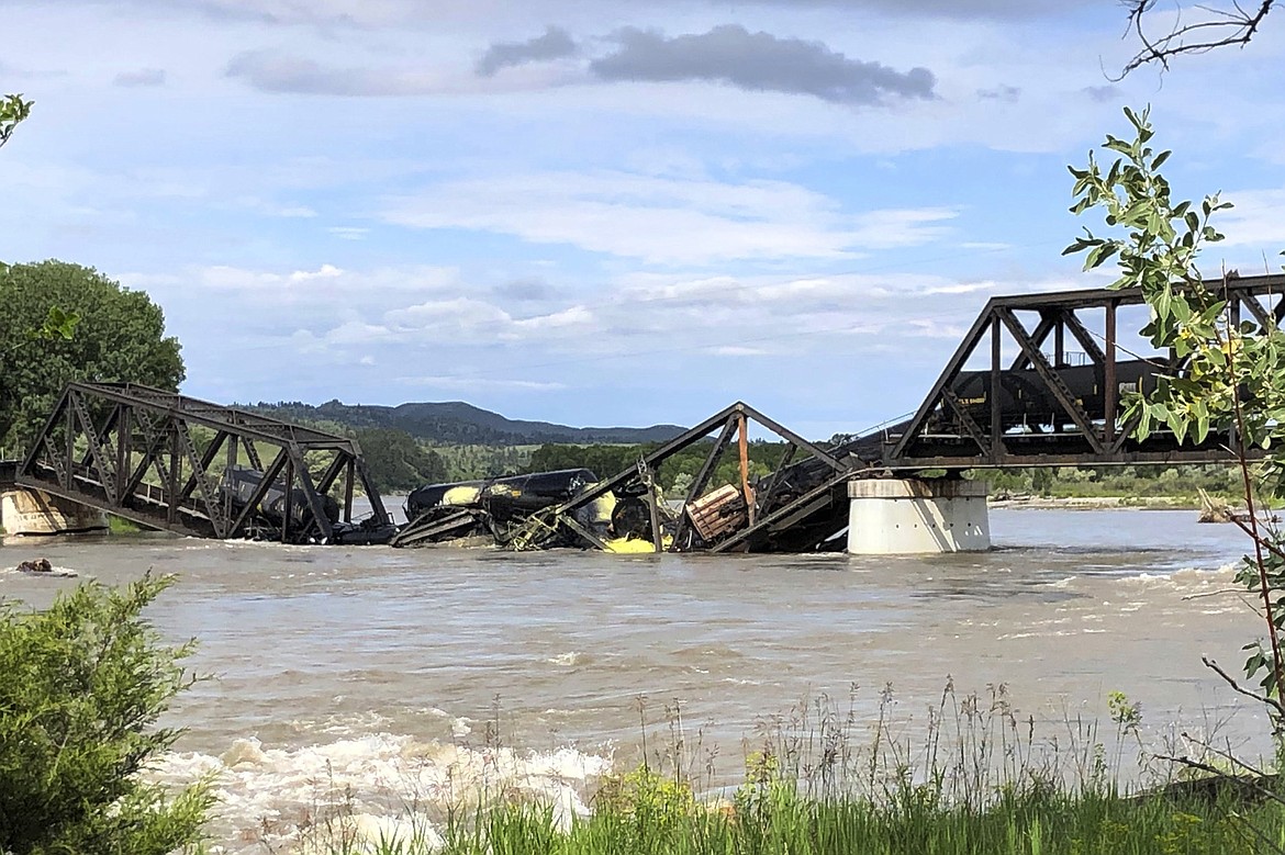 Several train cars are immersed in the Yellowstone River after a bridge collapse near Columbus, Mont., on Saturday, June 24, 2023. The bridge collapsed overnight, causing a train that was traveling over it to plunge into the water below. (AP Photo/Matthew Brown)