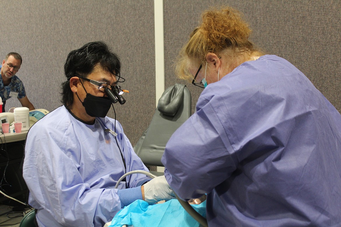 Dentist Sam Minagawa, left, said he volunteers to provide free care because it’s part of his mission to serve others. Minagawa and assistant Lorinda Sheldon, right, perform dental work for a patient Friday at a clinic sponsored by the Moses Lake Seventh-day Adventist Church.