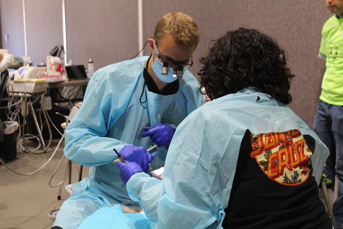 Dentist Greg Williams, left, and assistant Edie Torres, right, fix a filling for a patient. The two were among the volunteers providing free dental care at a clinic Friday in Moses Lake.