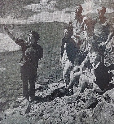 First and only woman naturalist in Glacier is Mary L. Dast, Midland, Mich., a graduate student in conservation education at Michigan State, seen here with a group of 26 at Iceberg Lake. There are 30 seasonal naturalists in Glacier. An important part of their job is to conduct walks into the mountains and present campfire talks.